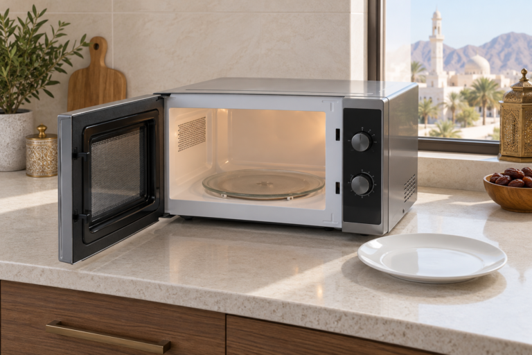 A countertop microwave with its door open and a plain plate beside it. | فرن ميكروويف على سطح مطبخ وبابه مفتوح وبجانبه طبق.